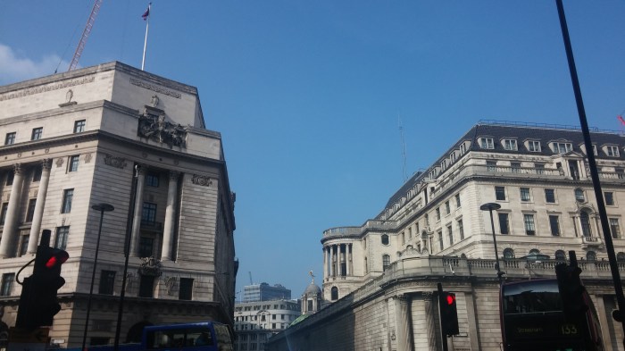 Photo of Georgian buildings hit by sun against a blue sky, traffic in the foreground